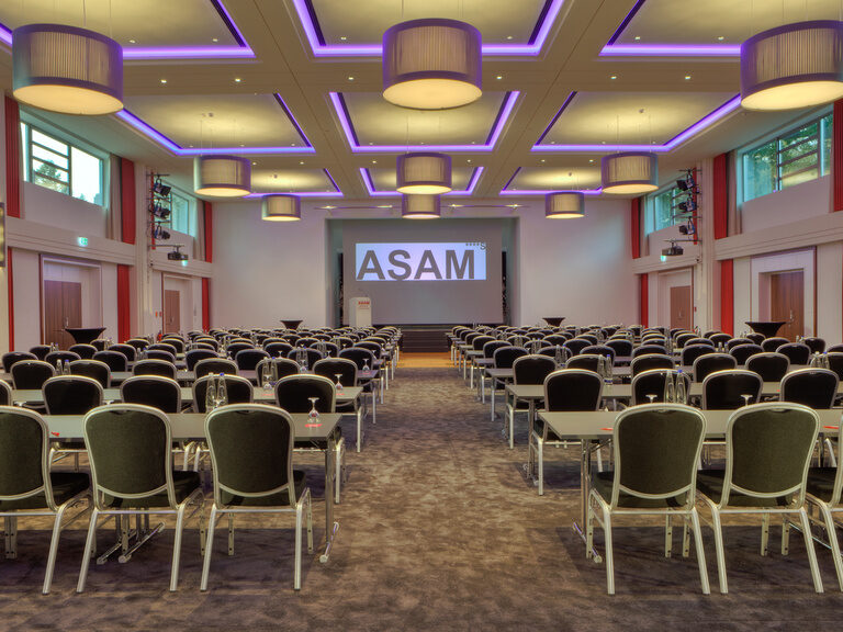Ein Konferenzsaal im Hotel ASAM mit eleganten Stühlen und Tischen.