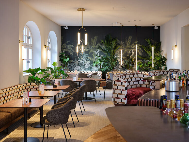 Ein stilvoll eingerichtetes Restaurant im Hotel ASAM mit zahlreichen Tischen und Stühlen.