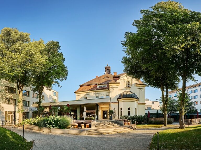 Die Außenansicht des Hotels ASAM mit Bäumen im Hintergrund.