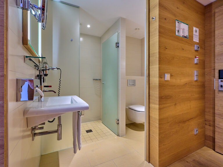 Modernes, helles Bad im 4-Sterne-S Hotel Asam Straubing mit Dusche, WC und Waschbecken.