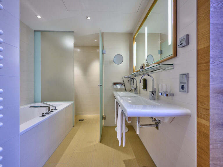 Modernes, helles Bad im 4-Sterne-S Hotel Asam Straubing mit Dusche, Badewanne, WC und Waschbecken.