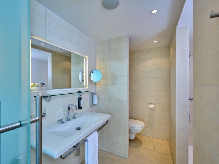 Badezimmer im 4-Sterne-S-Hotel ASAM Straubing mit Waschbecken, WC und Dusche.