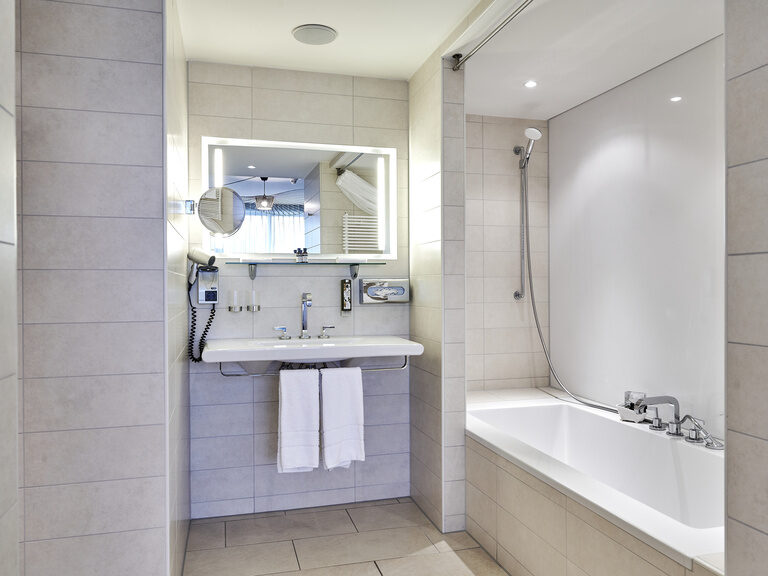Helles, modernes Bad mit Badewanne im Hotel Asam Straubing, elegant eingerichtet und einladend.