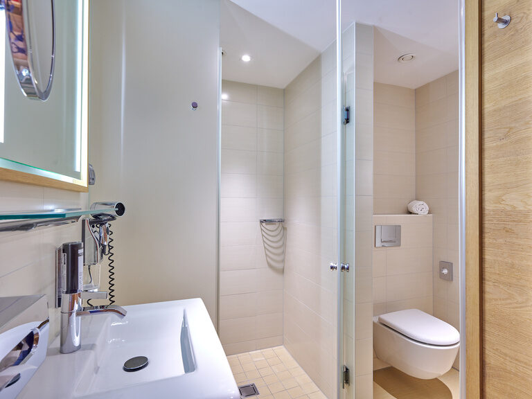 Helles Badezimmer mit Dusche im Businesshotel 4-Sterne-S Hotel Asam Straubing.
