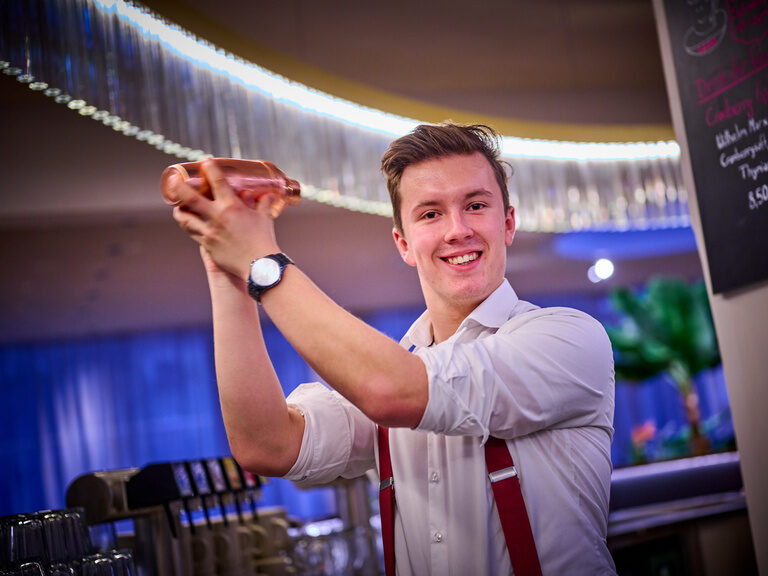 Barkeeper an der Bar des Hotel & Restaurant ASAM mit Shaker in der Hand.