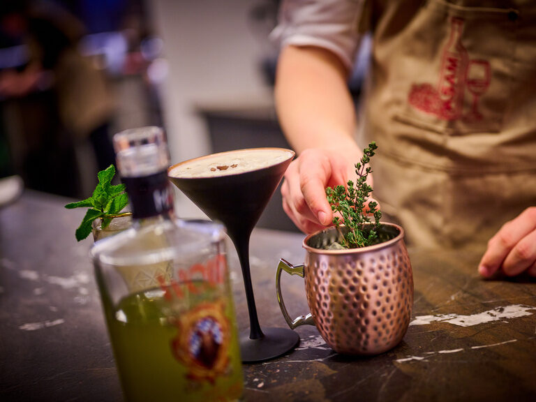Barkeeper garniert gerade einen Drink im Kupferbecher mit Thymian.