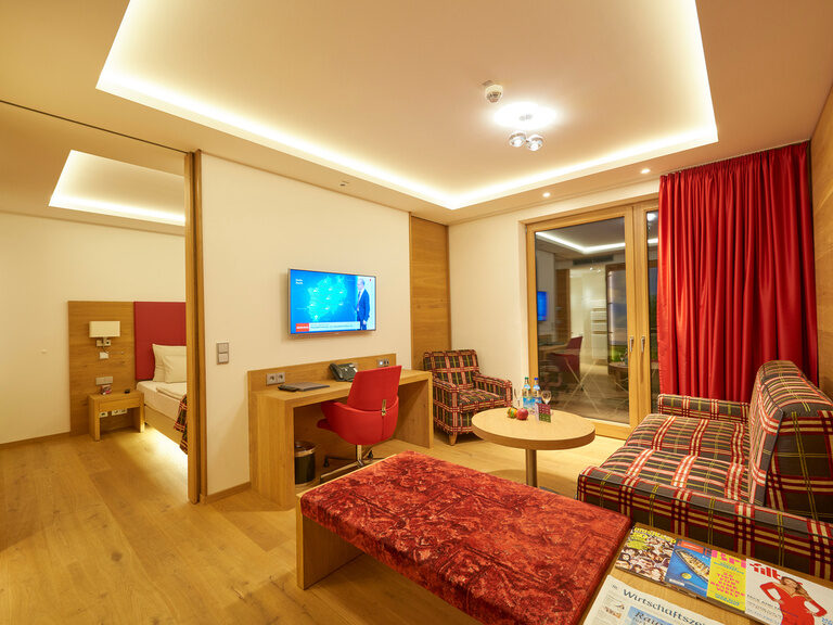 Baumwipfelsuite im 4-Sterne-S Hotel Asam Straubing mit getrenntem Wohn- und Schlafbereich und Balkon.