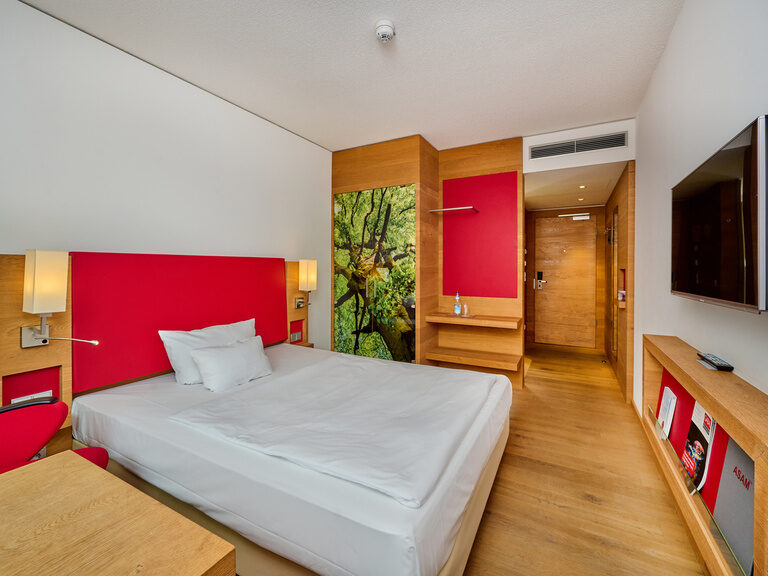 Business Einzelzimmer im Tagungshotel Asam Straubing mit Queensize-Bett, Schreibtisch, Parkett und warmen Farben.