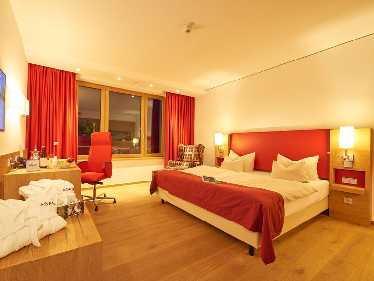 Abendliche Stimmung im Comfort Doppelzimmer des Hotel Asam Straubing, warm eingerichtet mit Holzboden und Echtholzmöbeln.