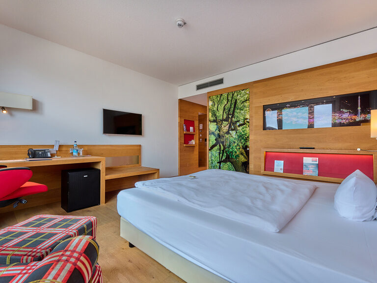 Helles Comfort Doppelzimmer im Businesshotel ASAM in Straubing mit Schreibtisch, gemütlichem Sessel, Parkettboden und warmen Farben