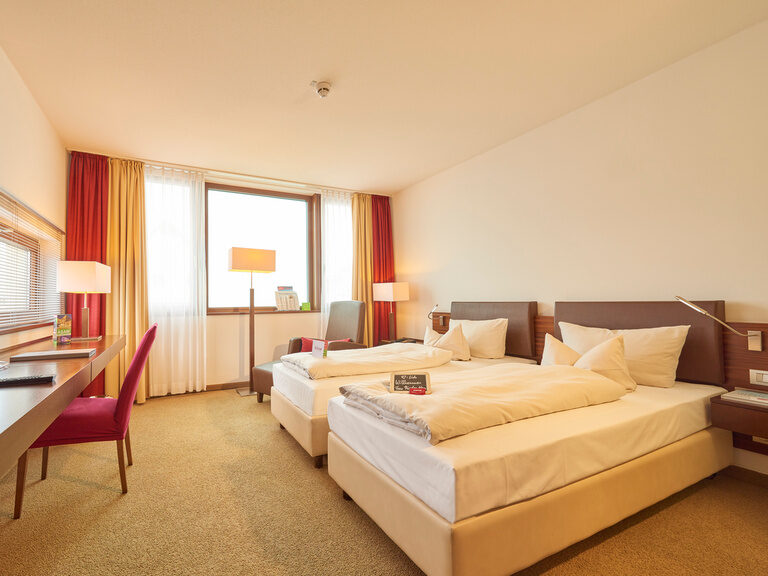 Doppelzimmer mit Twin-Betten im 4-Sterne-S Hotel Asam Straubing, gemütlich eingerichtet mit warmen Holzakzenten. Doppelzimmer mit Twin-Betten im 4-Sterne-S Hotel Asam Straubing, gemütlich eingerichtet mit warmen Holzakzenten.