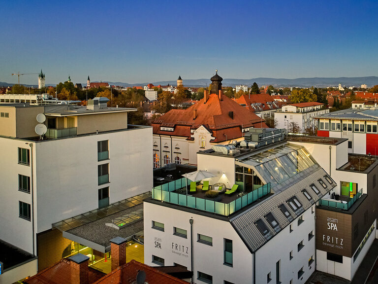 Drohnenaufnahme des Hotel ASAM in Straubing mit Blick auf den Wellnessbereich und das historische Offizierskasino im Hintergrund.