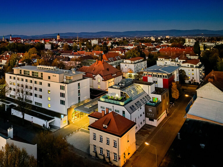 Drohnenaufnahme des 4-Sterne-S Hotel Asam bei Nacht, beleuchteter Wellnessbereich, zentral in Straubing gelegen. Drohnenaufnahme des 4-Sterne-S Hotel Asam bei Nacht, beleuchteter Wellnessbereich, zentral in Straubing gelegen.