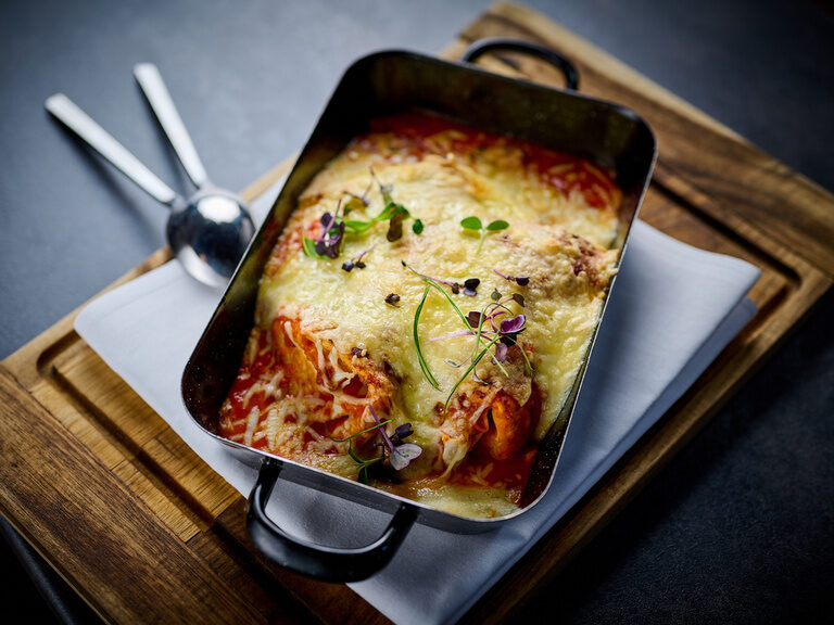Eine Auflaufform mit überbackenen Enchiladas auf einem Tisch im Restaurant ASAM in Straubing.