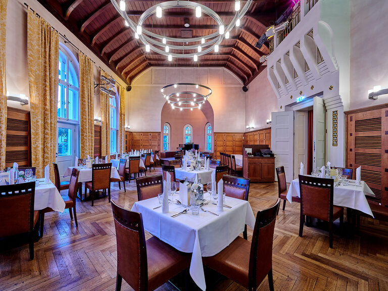 Ein festlich gedeckter Tisch im Festsaal Quirin, umgeben von eleganten Stühlen und gedämpfter Beleuchtung.