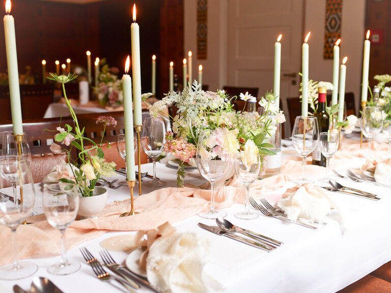 Eine elegante Tischdekoration mit Blumenarrangement und Kerzen auf dem Tisch im Festsaal Quirin.