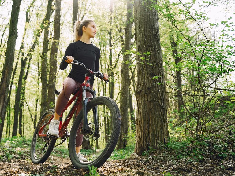 Eine junge sportliche Frau ist mit ihrem Fahrrad in einem Wald unterwegs