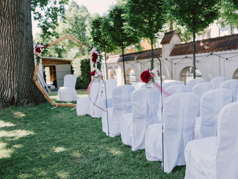 Stühle mit weißen Hussen im Garten des Hotel ASAM Niederbayern - geschmückt für eine Freie Trauung draußen.