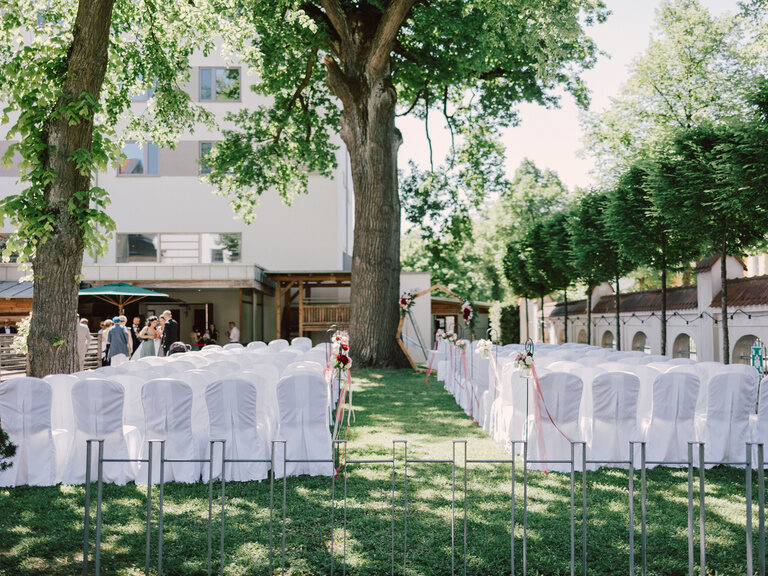 Stühle mit weißen Hussen im Garten des 4-Sterne-S Hotel ASAM in Straubing - vorbereitet für eine Freie Trauung.