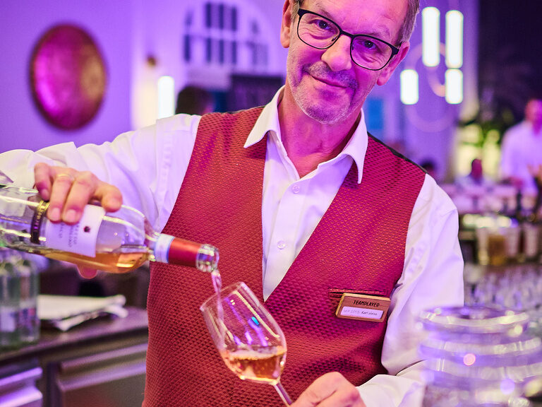 Restaurantleiter im Hotel & Restaurant ASAM in Straubing beim Einschenken eines Glases.
