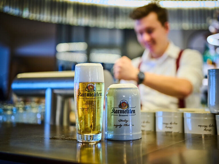 Regionales Karmeliten Bier an der Bar des Restaurant ASAM, im Hintergrund zapft ein Barkeeper Bier. Regionales Karmeliten Bier an der Bar des Restaurant ASAM, im Hintergrund zapft ein Barkeeper Bier.
