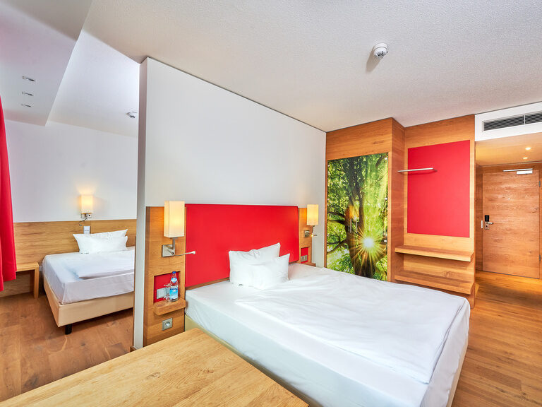 Gemütliches Mehrbettzimmer mit zwei Queensizebetten, optisch abgetrennt durch eine Wand. Gemütliches Mehrbettzimmer mit zwei Queensizebetten, optisch abgetrennt durch eine Wand.