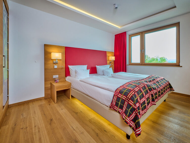 Abgetrenntes Schlafzimmer der Suite im 4-Sterne-S Hotel Asam Straubing mit Parkettboden und warmen Farben.