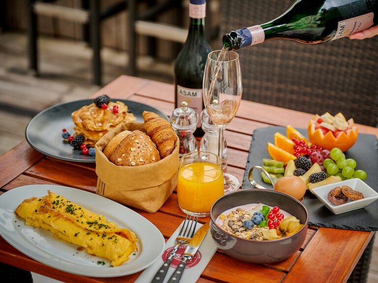 Ein edler Sekt wird in feine Trinkgläser im Hotel ASAM gegossen.