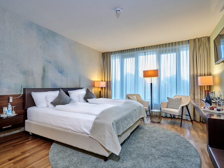 Superior-Zimmer im 4-Sterne-S-Hotel ASAM Straubing, elegant eingerichtet in blauen Tönen und Holzdetails.