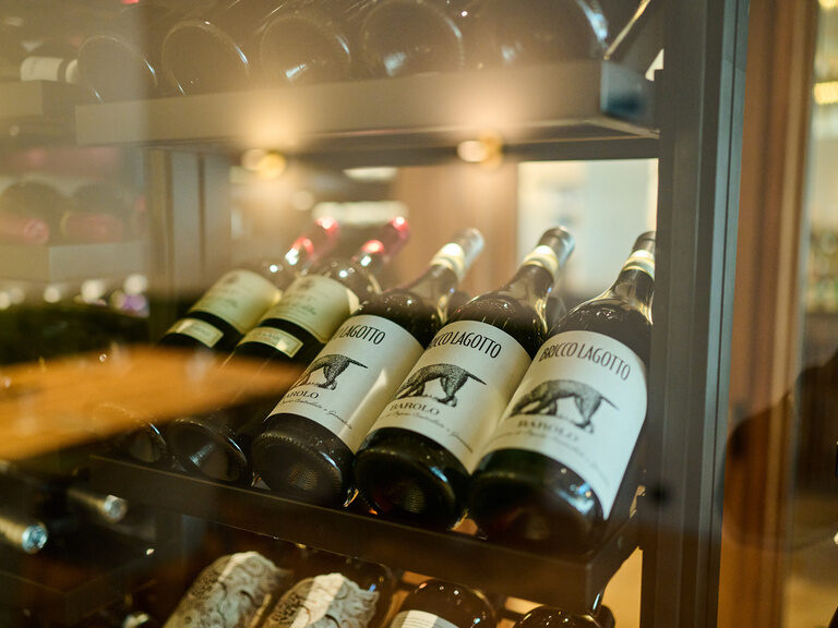 Blick auf Weinflaschen im begehbaren, gläsernen Weinschrank im Restaurant ASAM, Straubing.